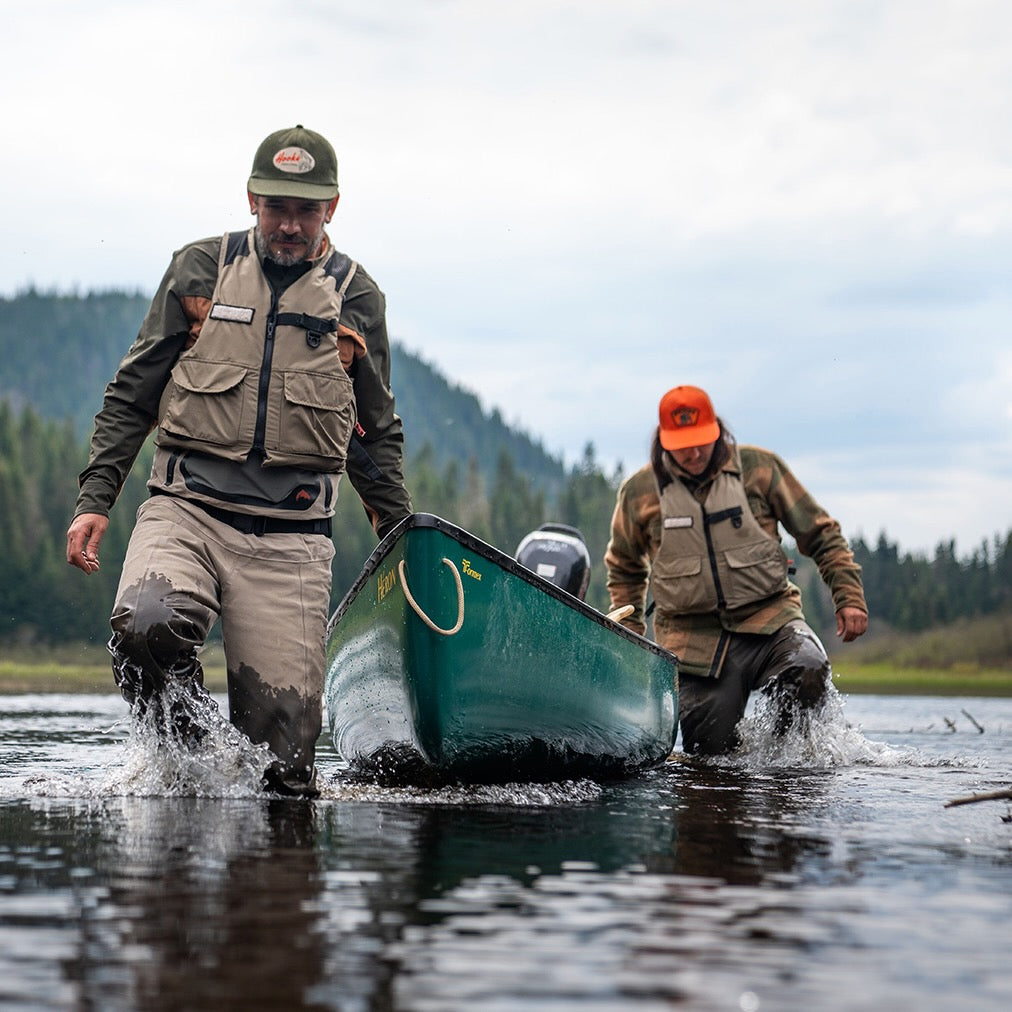 Two anglers wading through shallow water while guiding a composite canoe, highlighting the ideal setup for fishing canoes and options for canoes for fishing for sale.